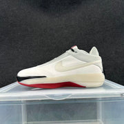 Side profile showing the white upper, Swoosh, black toe detail, and red outsole.