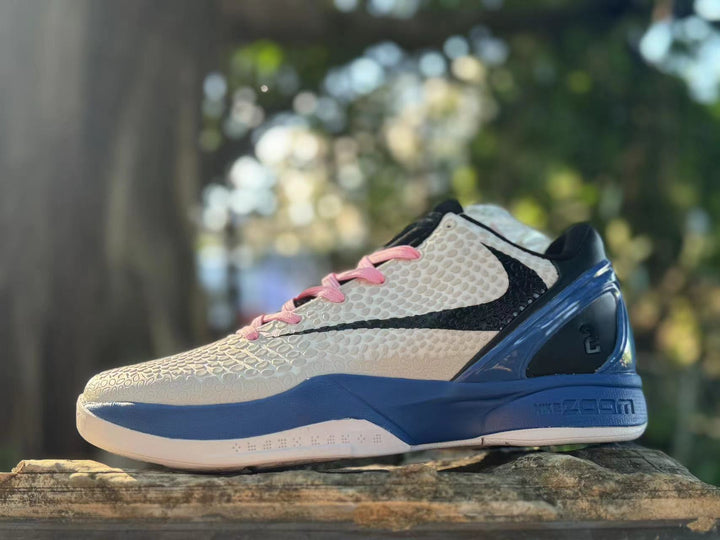 Side view of a white Nike Kobe 6 with a black Swoosh, pink laces, and blue heel and midsole.