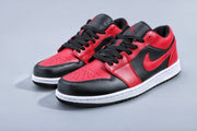 Pair of black and red low-top Jordan sneakers with white midsoles on a light background.