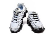 Front view of a pair of white and silver Nike Shox TL sneakers with black laces and soles.