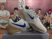 Pair of white and tan basketball sneakers displayed at an angle, showing blue swooshes and dark green collar lining.