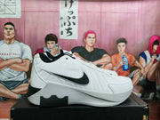 Side profile of a white Nike basketball sneaker with black Swoosh branding, padded upper, and sculpted sole.
