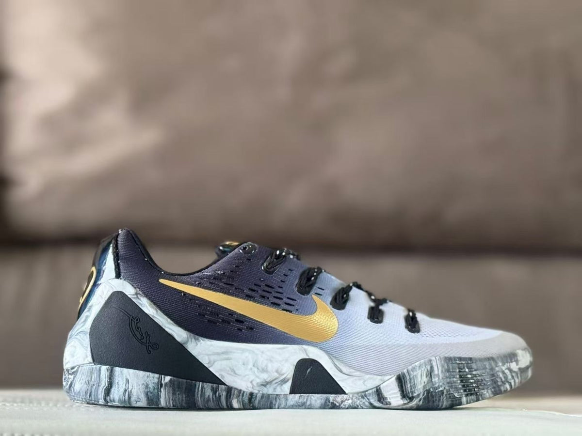 Side view of white Nike Kobe 9 GiGi sneakers with gold Swoosh branding, dark upper panels, and a gray marbled outsole.
