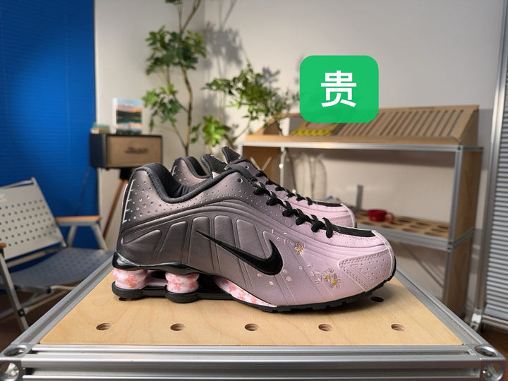 Pair of pink and gray Nike Shox sneakers with floral details and black laces.