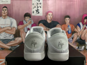 Rear view of white Nike sneakers showing padded collars, heel stitching, and embroidered heel branding.