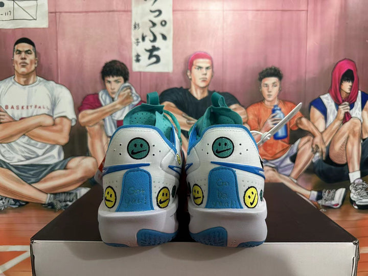 Rear view of white and teal basketball shoes with blue accents and smiley graphics on a box