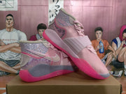 Angled view of two pink high-top sneakers showing the side branding, decorative overlays, laces, gray accents, and pink outsoles.