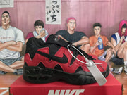 Side view of a black and red Nike sneaker showing layered panels, a black Swoosh, and a sculpted outsole.