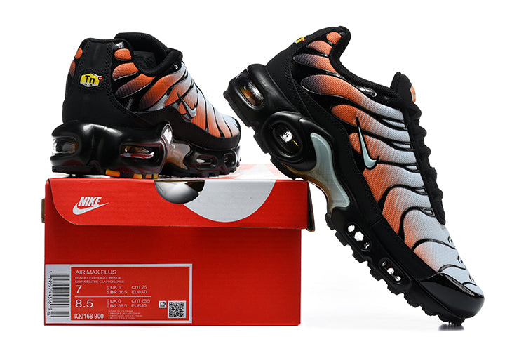 Nike Air Max Plus sneakers in black, white, and orange displayed with a shoebox