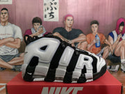 Side view showing the layered white lettering, black-and-white panels, and transparent sole cushioning.