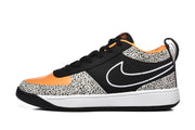 Side profile showing the black upper, white Nike Swoosh, orange toe area, spotted overlays, and white midsole.