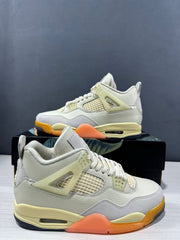 Close three-quarter view of the pair highlighting the light upper, mesh side panels, pale yellow supports, and orange outsole details.