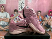 Angled view of the pink Nike basketball sneakers showing the side logo, laces, collar, and light-colored soles.