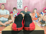 Front view of black and red basketball sneakers with black laces, red textured toe overlays, and small gold details.