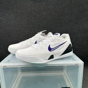 Pair of white low-top basketball shoes with purple Swoosh accents and black side panels