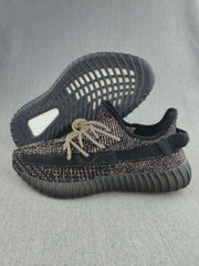 Pair of black Yeezy 350 V2-style sneakers showing the patterned knit upper, matching laces, and ribbed outsole.