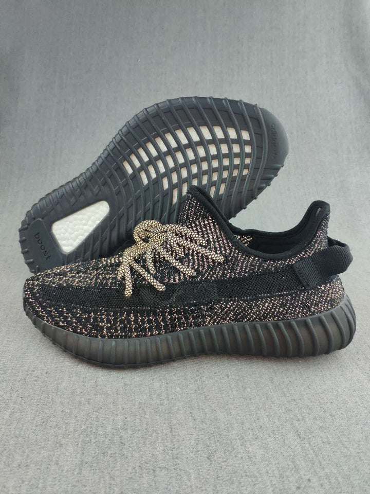 Pair of black Yeezy 350 V2-style sneakers showing the patterned knit upper, matching laces, and ribbed outsole.