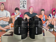 Rear view of black high-top sneakers showing white stitching, heel text, and light-colored soles.