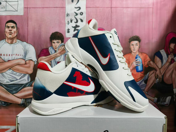 Pair of navy, white, and red Nike basketball sneakers displayed on a shoe box, showing side branding and layered upper panels.