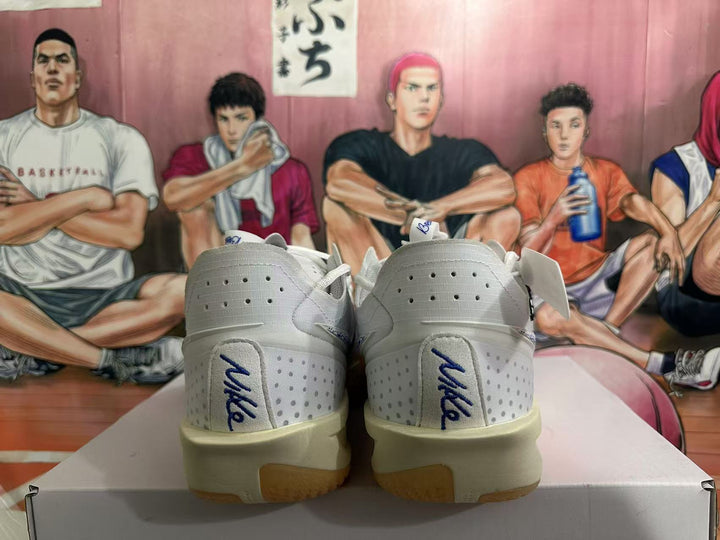 Rear view of white Nike basketball shoes with blue heel logos and amber-toned outsole sections.