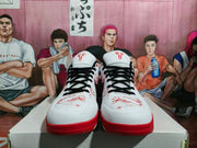 Front view of the pair showing white toe boxes, black laces, red patterned graphics, and red outsoles.