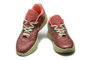 Front angled view highlighting the perforated tongues, green laces, orange lining, and patterned toe boxes.
