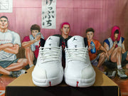 Front view of white Jordan high-top sneakers with white laces and black tongue logos.