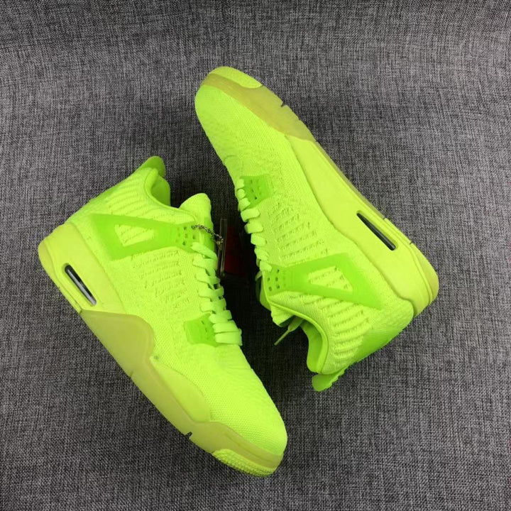 Pair of fluorescent green Jordan Air Jordan 4 sneakers shown from above on a gray fabric surface.