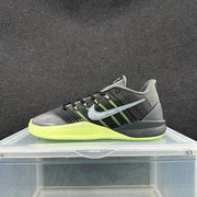 Side view of black and gray Nike sneakers with bright green soles and contrasting Swoosh branding.