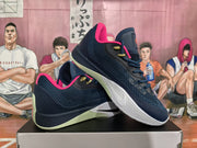 Angled view of dark navy Nike basketball sneakers showing the textured upper, pink collar lining, white midsole, and pale green outsole.