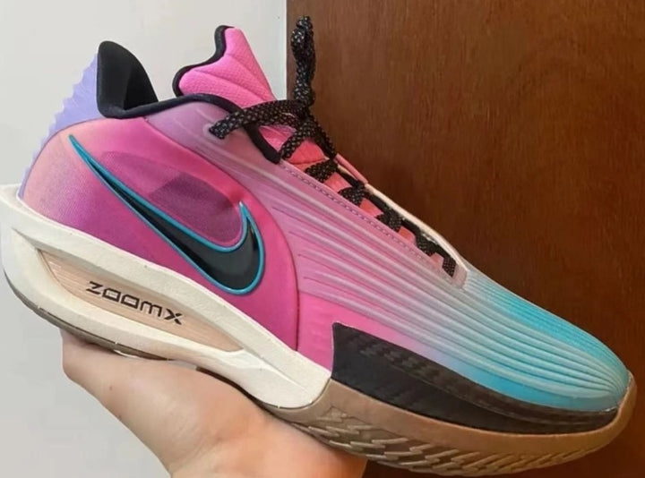 Pink and blue Nike sneaker with a black Swoosh, black laces, ZoomX midsole branding, and a textured outsole.