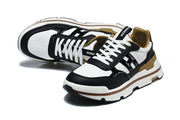 Pair of black and white low-top sneakers with white laces and tan lining, shown from above and at an angle.