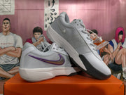 Angled view of the gray and white Nike basketball shoes showing purple Swoosh accents and textured panels.