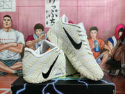 Angled view of white Nike basketball sneakers with black Swooshes and patterned outsole detailing.