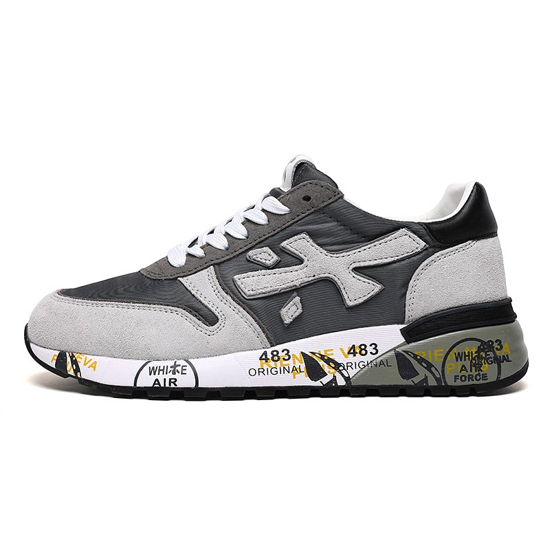 Side view of grey and white Premiata low-top sneakers with white laces, a contrasting side logo, and a graphic-printed sole.