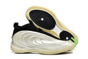 Cream and black basketball shoes shown from the side and outsole, with green heel accents and circular traction zones.