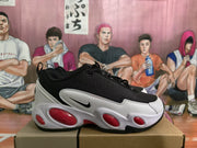 Side view of a black Nike sneaker with white overlays, red oval sole accents, and a visible Swoosh.