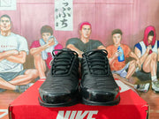 Front view of a pair of black Nike sneakers showing the laces, layered toe panels, and rounded toes.