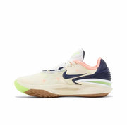 Cream Nike GT Cut 2 sneaker with a dark navy Swoosh, pink collar, neon green accents, and a gum-colored outsole.