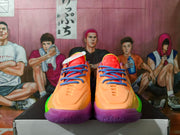 Front view of orange basketball shoes with blue laces and purple soles