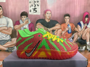 Side view showing the black Swoosh and red outsole on a green and red basketball shoe