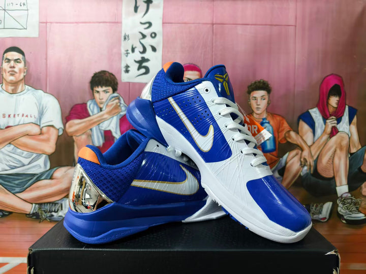 Pair of blue and white Nike Kobe basketball shoes shown at an angle, with gold accents and reflective-looking heel panels.