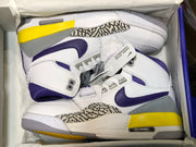 Top-down view of the pair inside a shoe box, showing the white and purple uppers, yellow accents, and patterned side panels.