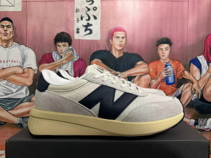 Side view of off-white and black New Balance U370 sneakers with a light-colored sole.