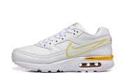 Side view of a white Nike Air Max sneaker with gold accents and a visible heel Air unit.
