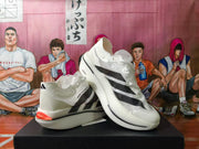 White adidas shoes shown at an angle with black stripes and red heel accents