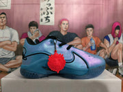 Side view of an iridescent blue Nike basketball shoe with black accents, a red charm, and patterned translucent outsole