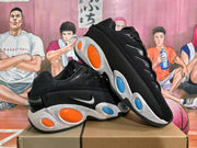 Angled view of two black Nike sneakers highlighting the textured side panels, Swoosh branding, speckled midsoles, and colored oval details.