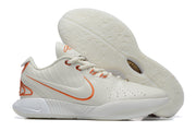 White Nike basketball shoe with orange trim and a pale outsole.