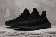Pair of black Yeezy 350 V2 sneakers shown from a three-quarter front angle.